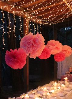 the table is set up with candles and paper pom - poms on it