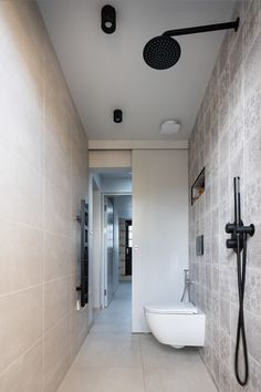 a bathroom with a white toilet sitting next to a wall mounted faucet and shower head