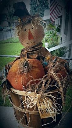 a scarecrow sitting in a basket filled with pumpkins