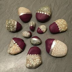 nine painted rocks with designs on them sitting on a table next to a cell phone