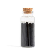 black and white matchsticks in a glass jar with cork top on a white background