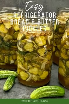 three jars filled with pickles sitting on top of a table next to cucumbers