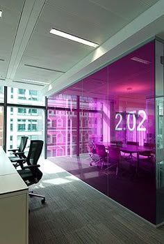 an empty conference room with purple lighting in the center and large windows on both sides