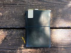 a black leather notebook sitting on top of a wooden table