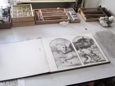 an open book sitting on top of a table next to some drawers filled with books