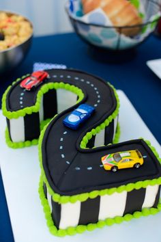 two birthday cakes with cars on them are sitting on a white tablecloth covered plate