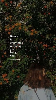 a woman standing in front of a tree with oranges on it and the words beauty is everything that's hiding behind her being you