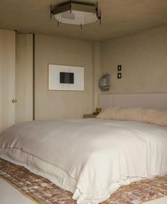 a bed with white sheets and pillows on top of a carpeted floor next to a doorway