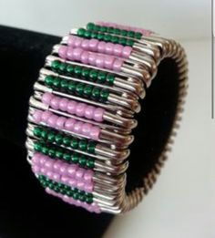 pink and green beaded bracelet sitting on top of a black stand