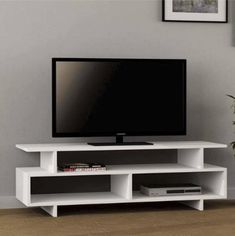 a flat screen tv sitting on top of a white entertainment center next to a potted plant