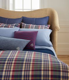 a bed with blue and red plaid sheets, pillows and blankets on top of it