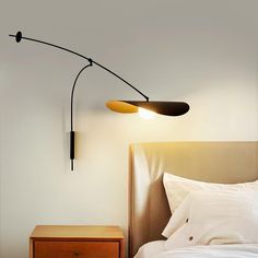 a lamp that is on the side of a wall next to a bed with white sheets