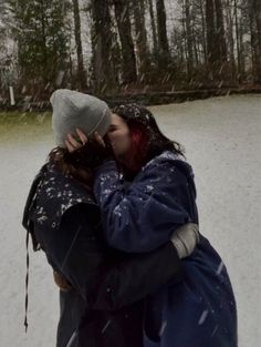 two people standing in the snow kissing each other