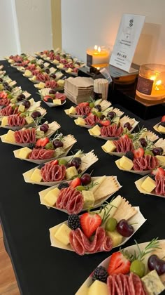 a long table topped with lots of different types of cheeses and fruit on top of plates