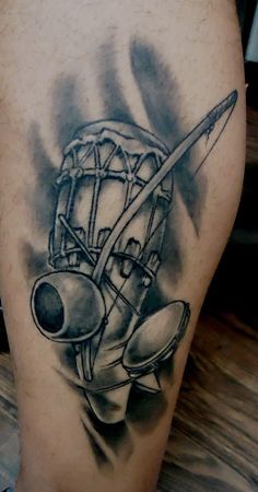 a black and white photo of a baseball glove, bat and ball tattoo on the leg