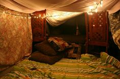 a bed covered in blankets and lights under a canopy