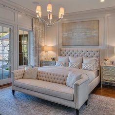 a large bed sitting in the middle of a living room next to a window with french doors