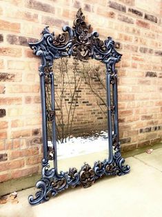 an ornate mirror is leaning against a brick wall