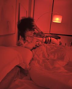 a woman laying in bed with red light coming from her head and arm behind her