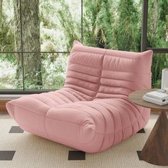 a pink reclining chair sitting on top of a rug in front of a window