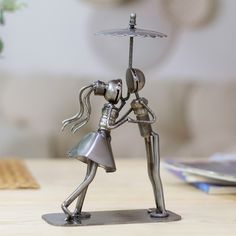 a metal figurine holding an umbrella on top of a table