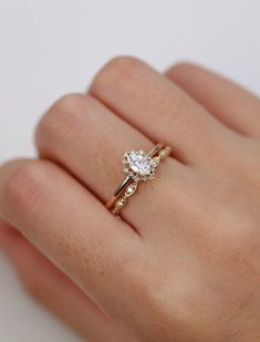 a woman's hand wearing a gold ring with a white diamond on the side