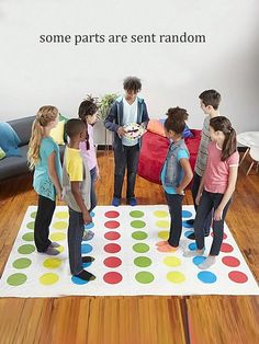 a group of children standing around a giant polka dot mat on the floor next to a couch