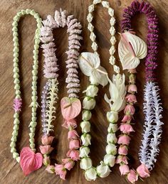 several different types of flowers are laid out on a wooden surface, one is pink and the other is white