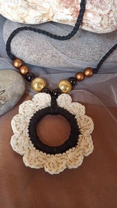 a crocheted necklace with beads and pearls on it sitting on top of a piece of cloth