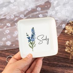 a person holding a square plate with flowers on it and the word sorry written in cursive writing