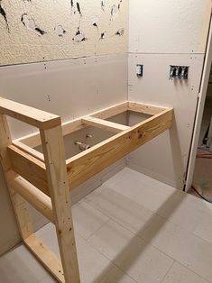 an unfinished desk in the corner of a room with white walls and tile flooring