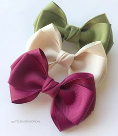 three different colored bows on a white surface