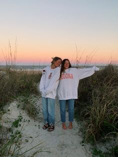 two girls standing on the beach with their arms around each other