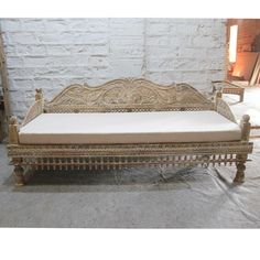 an antique wooden daybed with white cushions