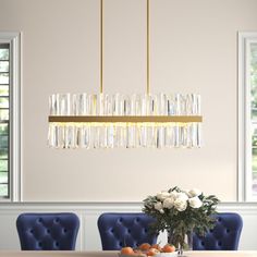 a dining room table with blue chairs and a chandelier hanging over it's head