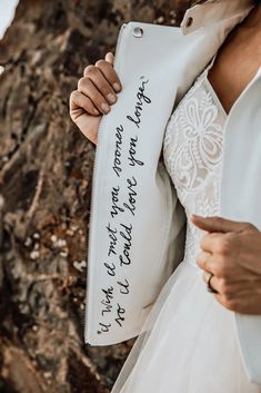 a woman in a wedding dress holding up a white jacket with writing on the side