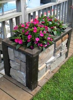 a planter with pink flowers in it sitting on a porch next to the water