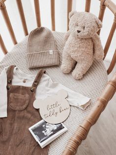 a teddy bear sitting on top of a wooden chair next to a baby's bib