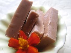 three pieces of chocolate sitting on top of a white plate next to a red flower