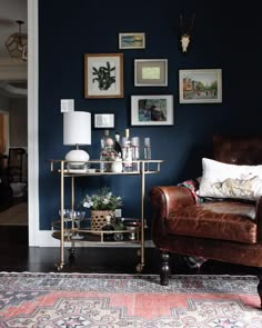 a living room filled with furniture and pictures hanging on the wall behind a leather chair