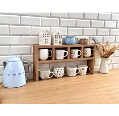 a shelf filled with cups and mugs next to a tea kettle on top of a wooden table