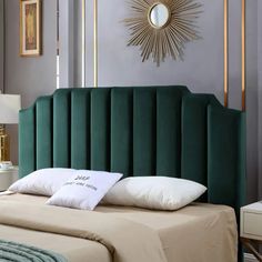 a green headboard on a bed with white pillows and a gold starburst above it