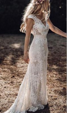 a woman in a white wedding dress holding her hand out to the side with trees in the background