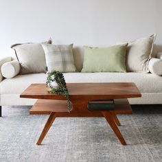 a coffee table sitting on top of a rug in front of a couch with pillows