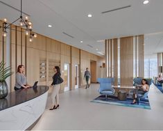 people are sitting at the reception desk in an office building with wood paneling on the walls