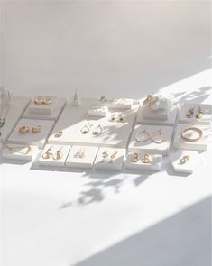 an assortment of jewelry displayed on white pedestals with shadows from the ceiling behind them