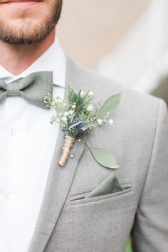 a man wearing a gray suit with a boutonniere on his lapel