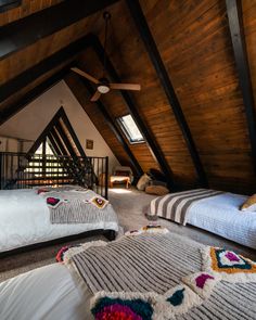 two beds in a loft with wooden walls and ceiling fans on either side of them