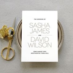 a pair of gold scissors next to a wedding card