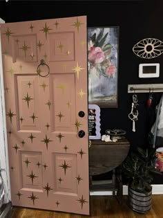 a pink door with gold stars painted on it in a black room next to a potted plant